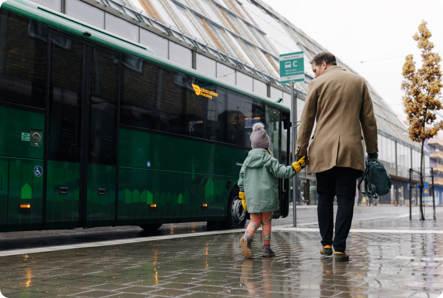 Foto på en flicka med sin pappa som står vid en buss från Länstrafiken Blekinge.